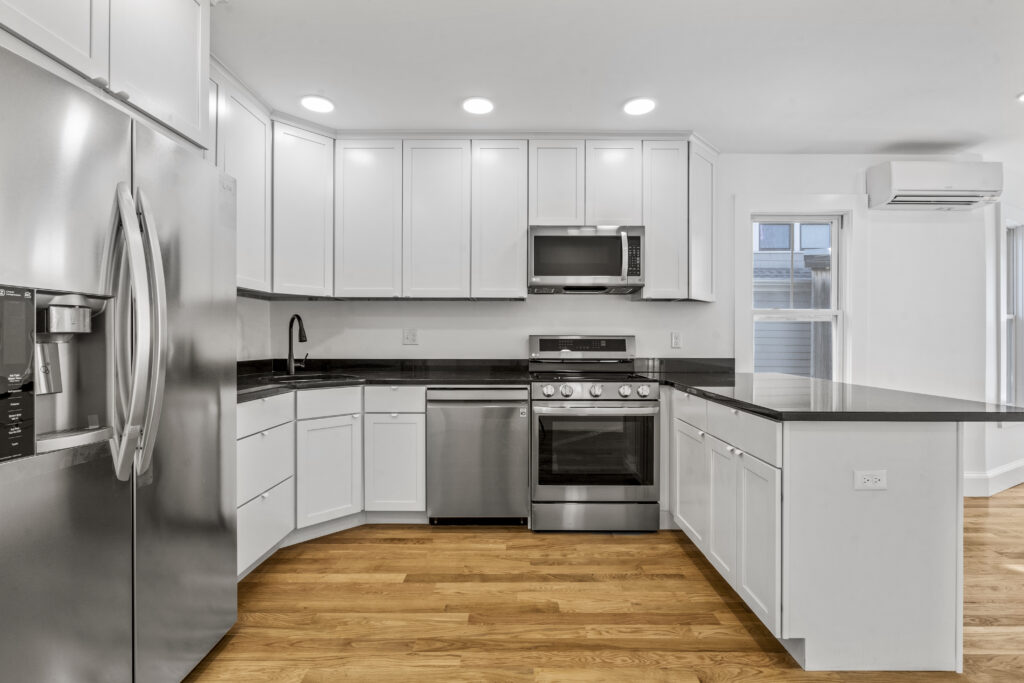 White L-shaped kitchen with dark counters and stainless steel appliances
