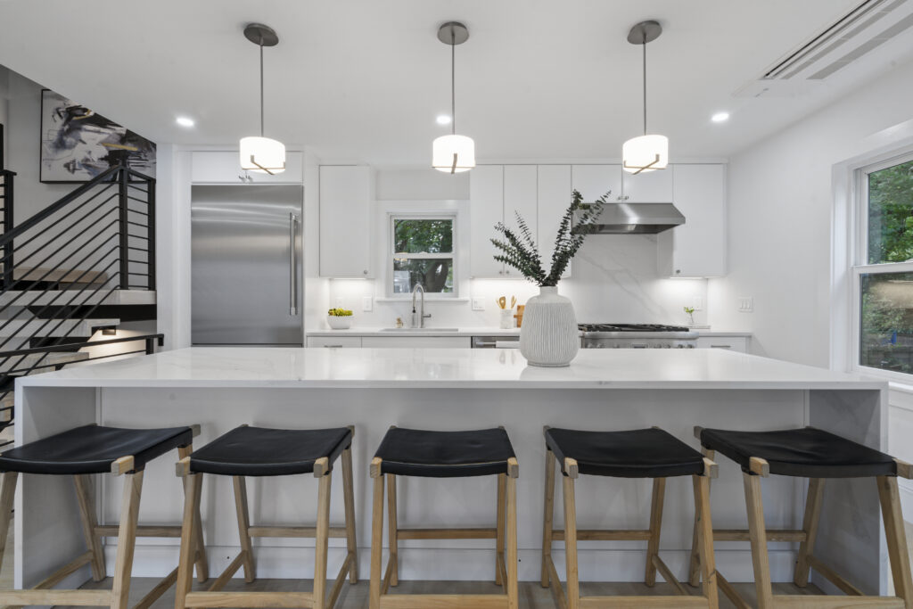 White kitchen island with black stools and pendant lighting
